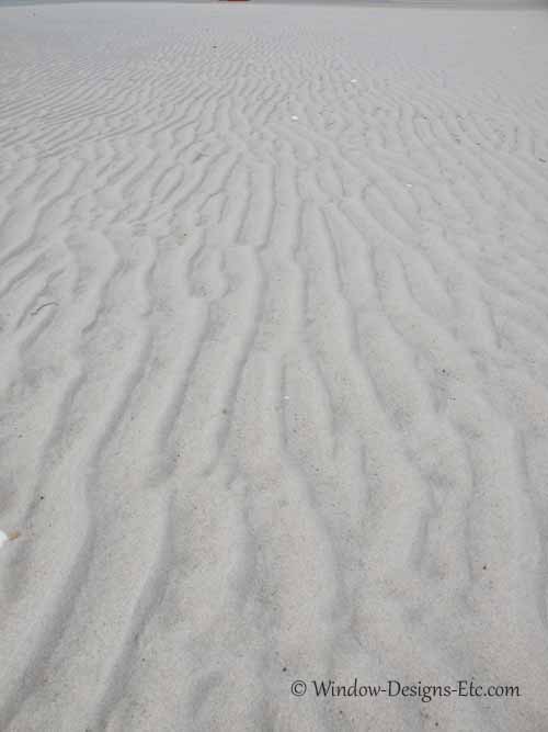 Beachcombing for a shell valance. Rippled sand dotted with large clam shells