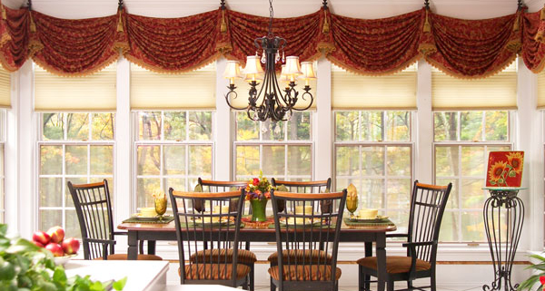 Window valance across multiple windows in a rust and gold swagged fabric creates a unique custom top treatment for a Worcester, MA dining area.